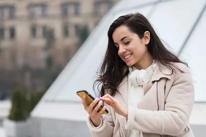 Essential Tips To Stay Connected While Travelling Woman smiling while holding smartphone